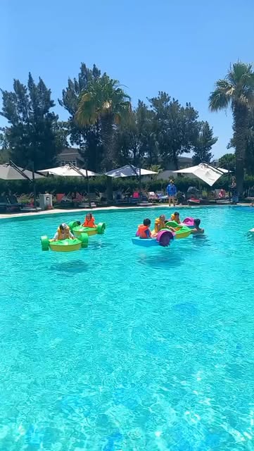 Otel bahçesinde kurulan dev yüzme havuzunda havuz arabalarıyla oynayan çocuklar